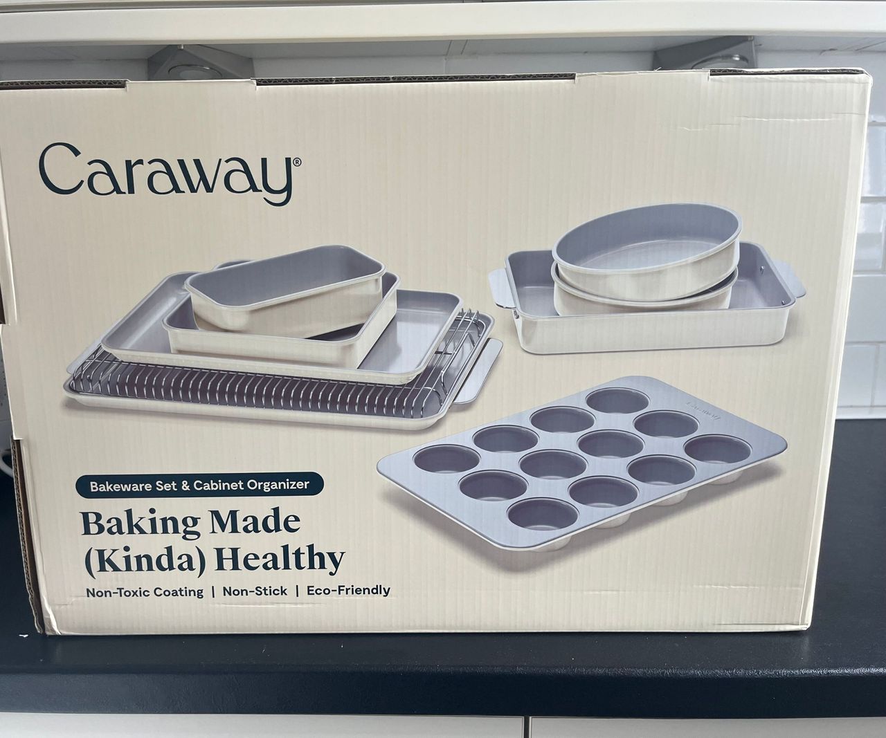 A box of Caraway bakeware on a black kitchen counter.