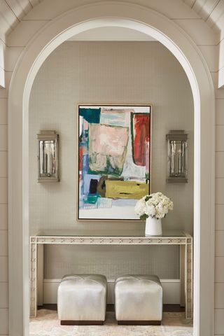arched doorway to hall with colourful modern artwork console table and cube stools