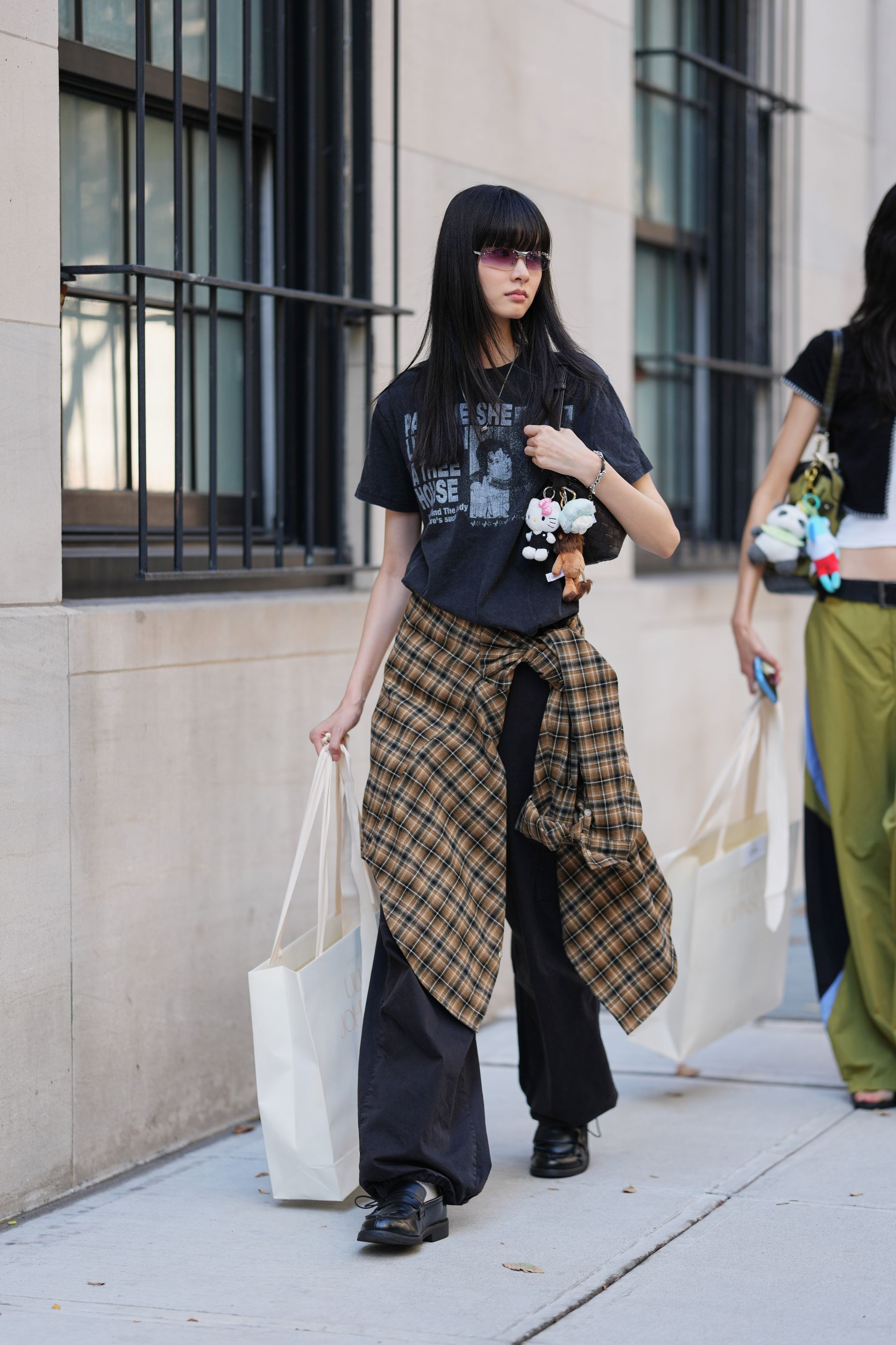 A woman wears a plaid shirt tied around her waist.