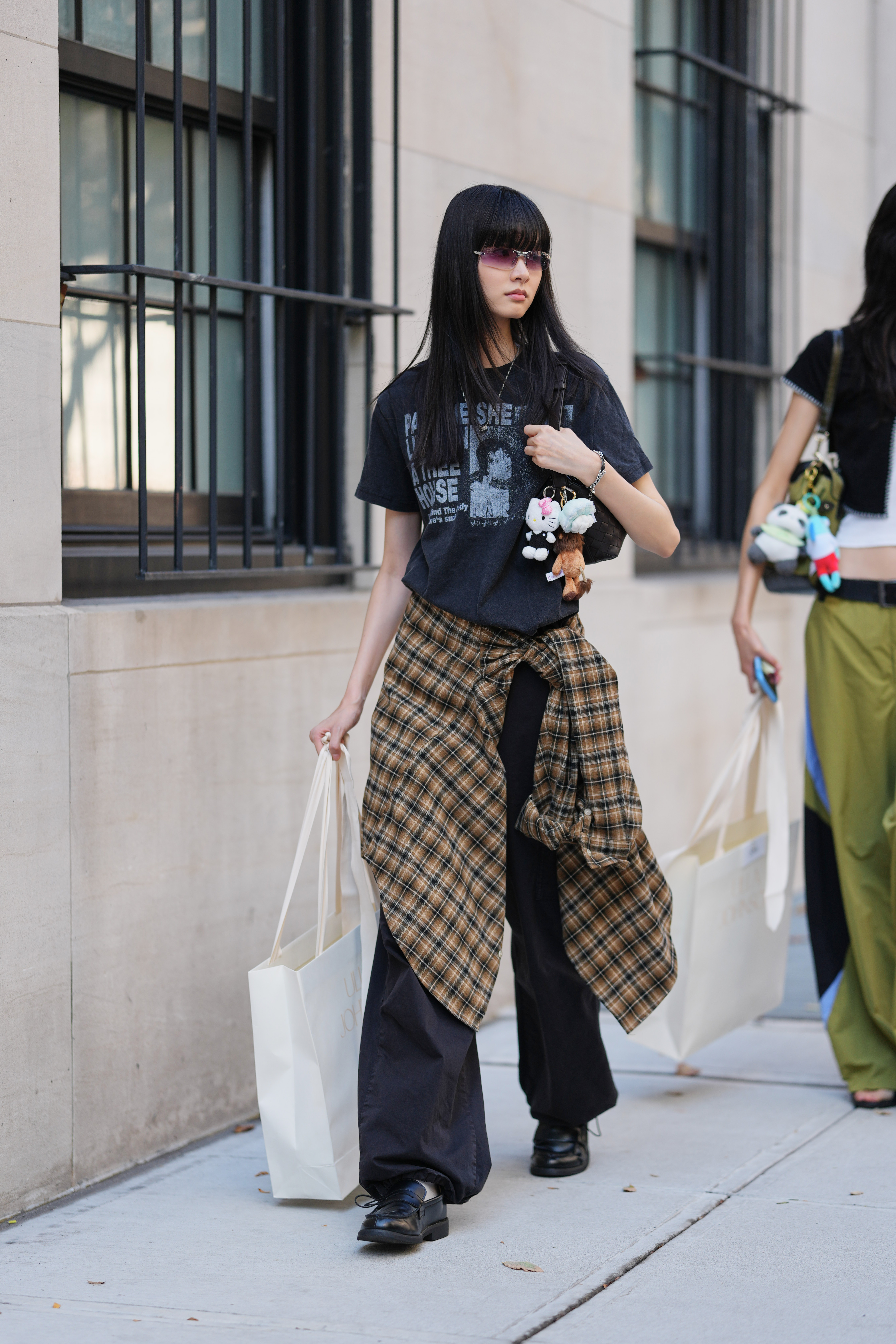 A woman wears a plaid shirt tied around her waist.