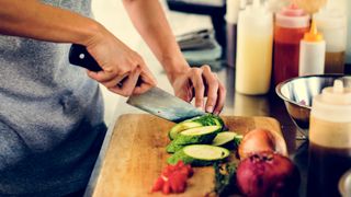 Someone preparing vegetables with a kitchen knife