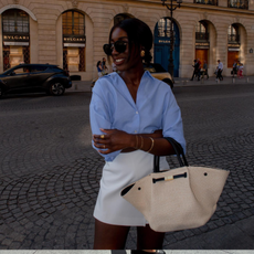 Aida wears a blue shirt, white skirt and raffia woven bag.