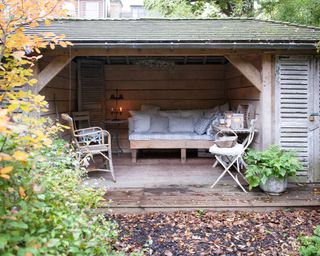 A wooden garden room with wooden garden sofas and cushions inside