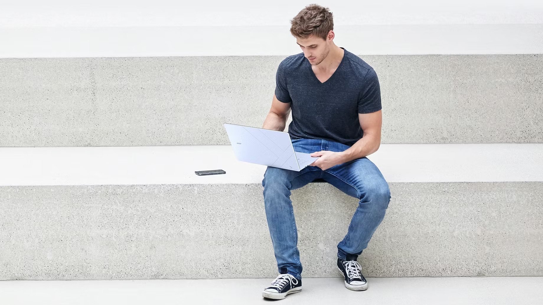 Acer Swift Blade 14 being used by a person sat on a concrete step outside