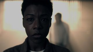 A close up of Moira with the silhouette of a man behind her in The Handmaid's Tale season 6