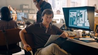 Skyler Gisondo sits at his desk while hilding a copy of the Daily Planet in Superman.