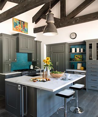 kitchen with dark gray cabinets, white wools, dark wood ceiling beams and kitchen island