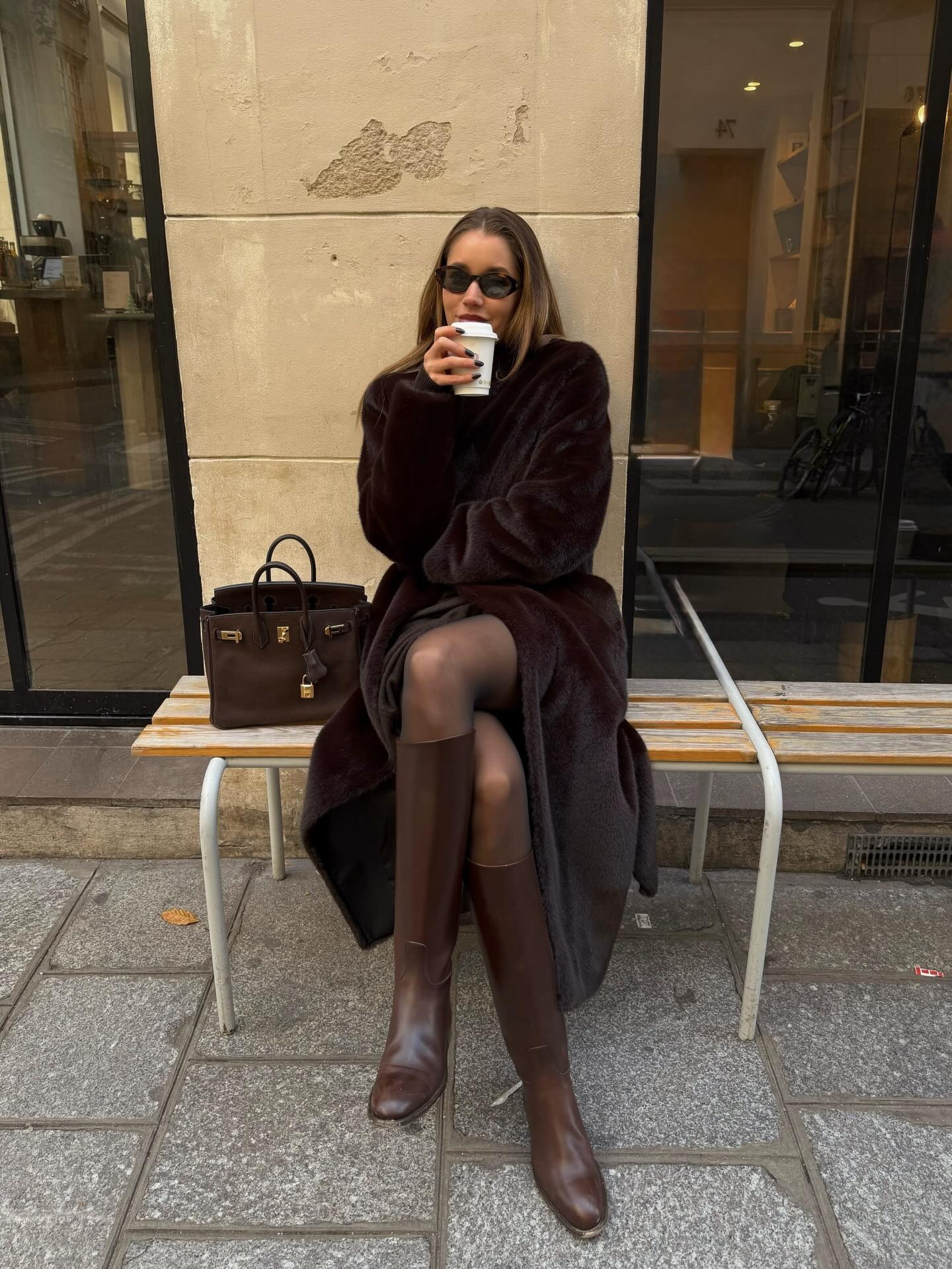 A woman in a dark brown faux-fur coat and brownboots
