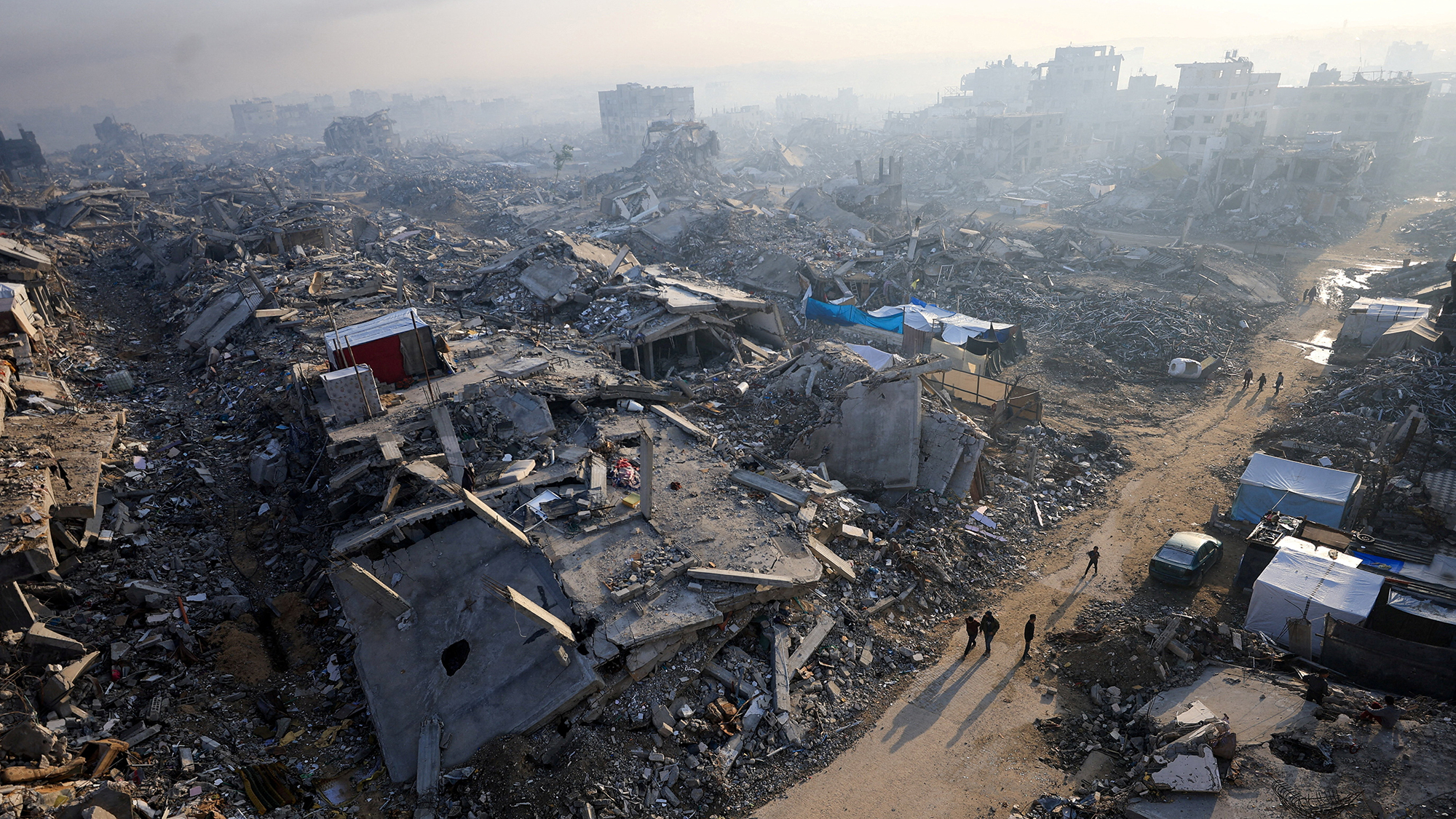 Palestinians walk past the rubble of destroyed buildings in Gaza City