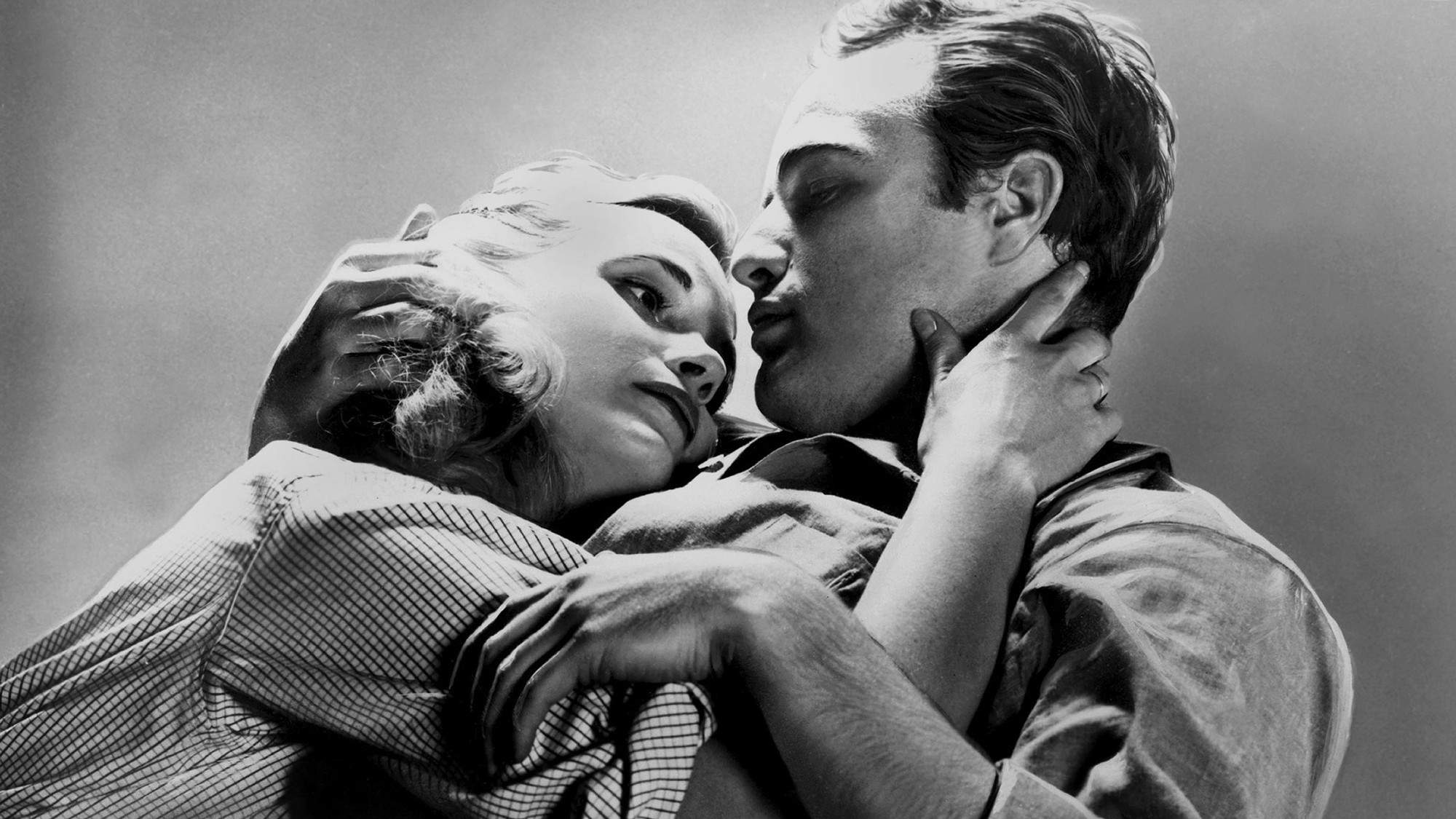 film still of Eva Marie Saint and Marlon Brando, in black and white, embracing in ‘On the Waterfront’