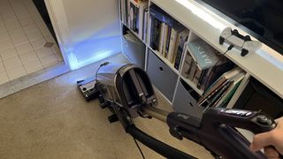 Shark POWERDETECT Upright Vacuum vacuuming carpet in small room, with blue LED lights from the floor head