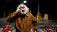 Mike Matthews from Electro-Harmonix posing with a cigar in front of stacks of pedals in boxes