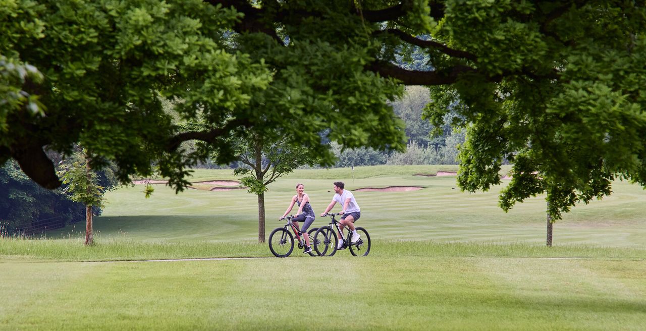 A couple cycling on the grounds of a golf course