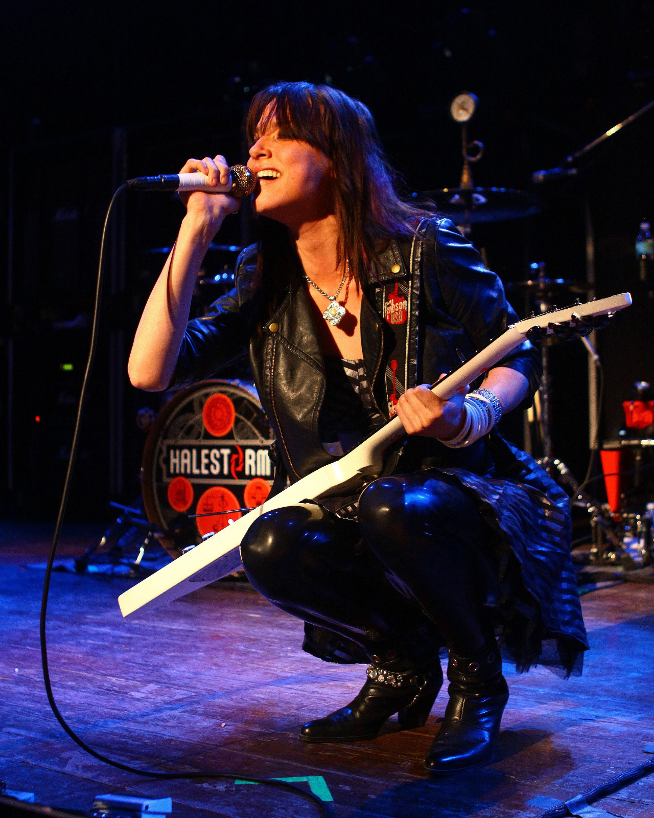 Lzzy Hale crouching and singing on stage in 2009