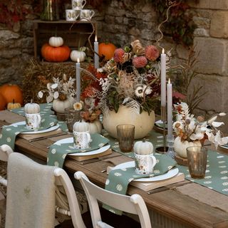 Halloween tables cape with green polka dot table linen, dried flowers, candles and pumpkins