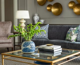 gold glass coffee table in a modern living room with grey walls