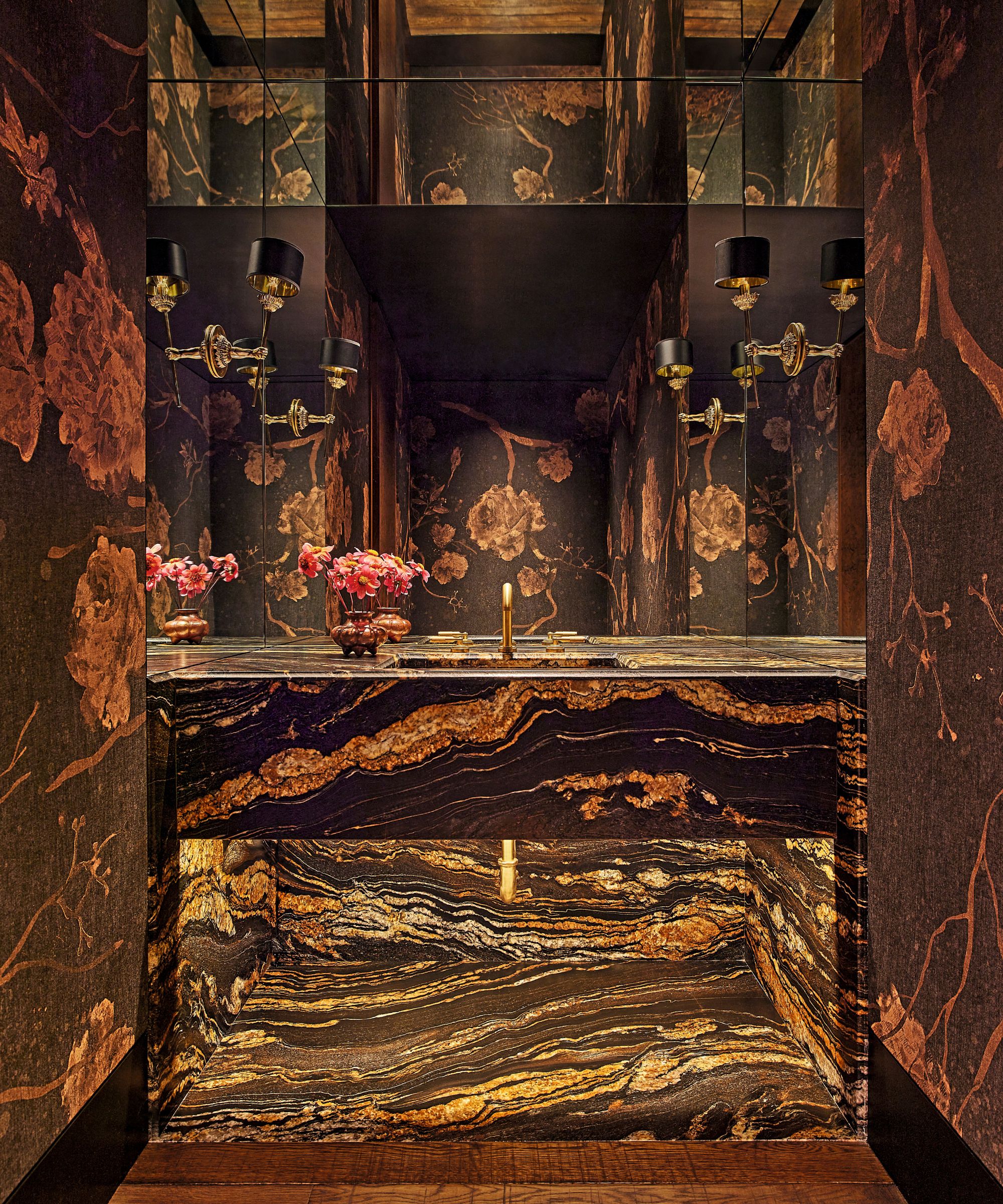 Powder room featuring dramatic gold-veined black marble vanity, dark floral wallpaper, wall sconces, and gold plumbing fixtures