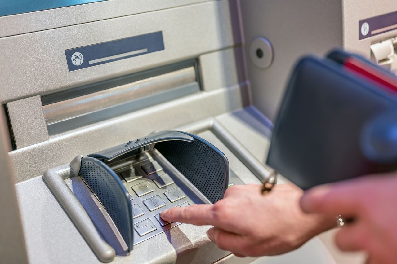 Person entering a PIN number at ATM.