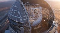 A metallic dome structure in the desert with sunlight making it look quite beautiful.