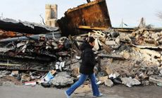 A woman walks by destroyed homes and businesses in Queens, New York: Hurricane Sandy's economic damage played havoc with the national GDP.