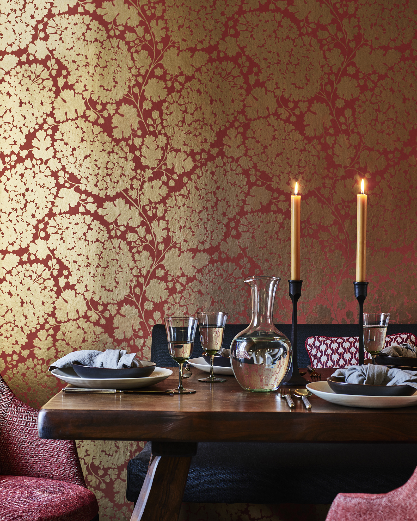 gold wallpaper design on red background, wooden table, red armchairs, bench, table setting