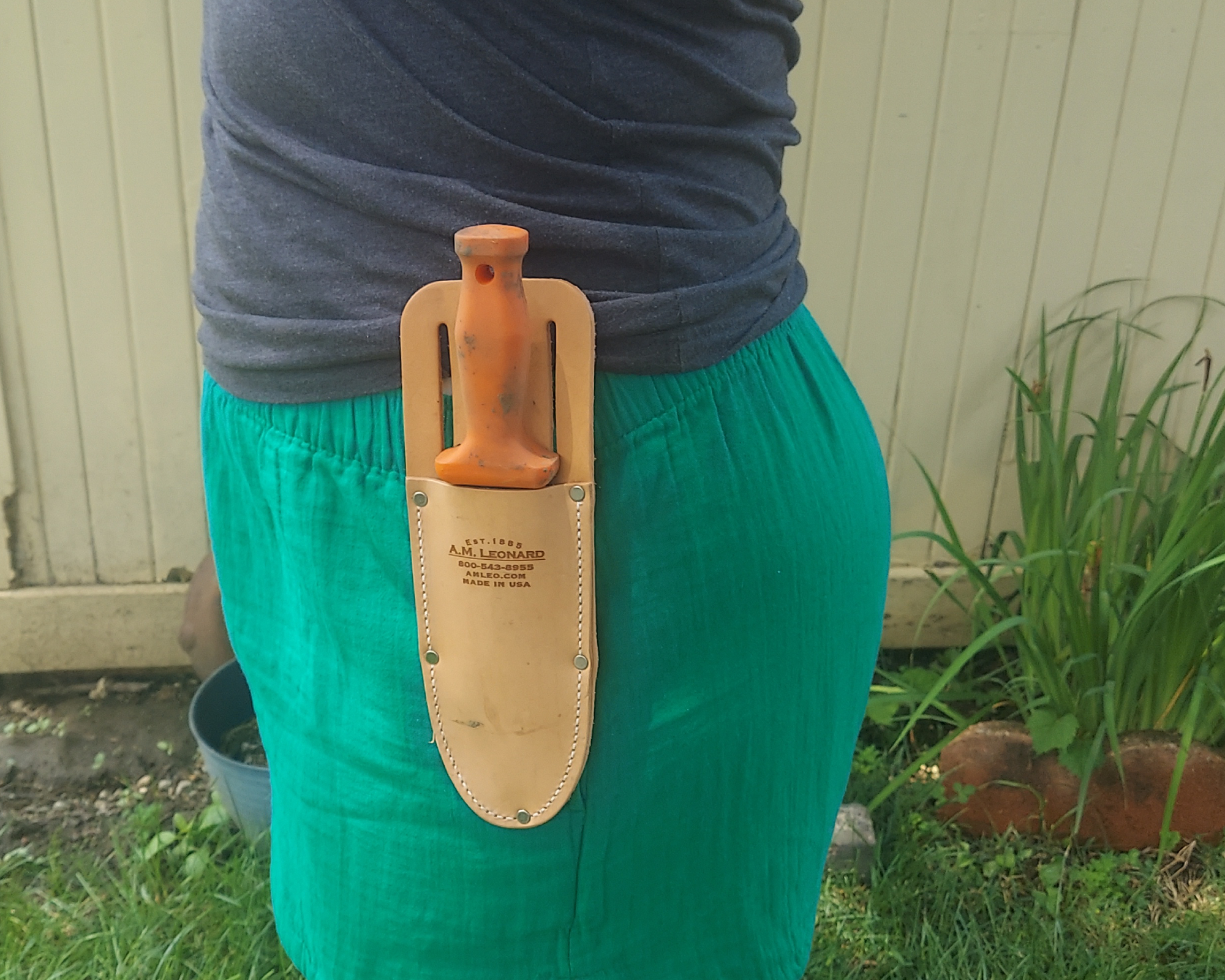 Gardener has leather sheath with soil knife clipped to belt