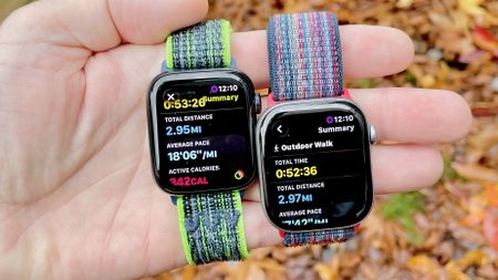 Close-up of the Apple Watch SE 3 and Apple Watch Series 11 in a user's hand with a colorful, out-of-focus background