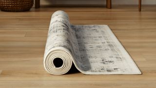 Wooden floorboards with rolled rug from Ruggable on it