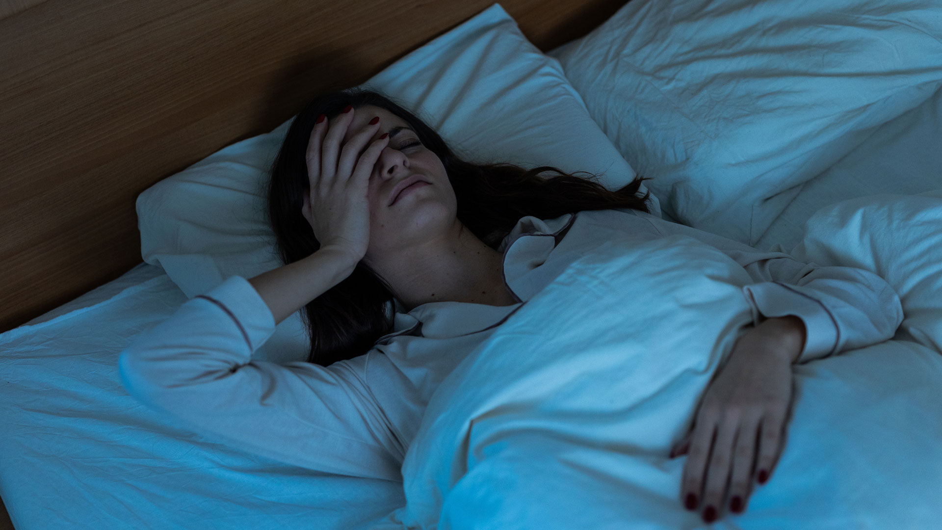 A woman lies awake in bed, unable to sleep