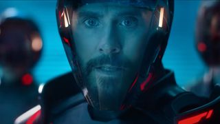 a bearded man in a motorcycle helmet with a clear visor looks concernedly at something behind the viewer