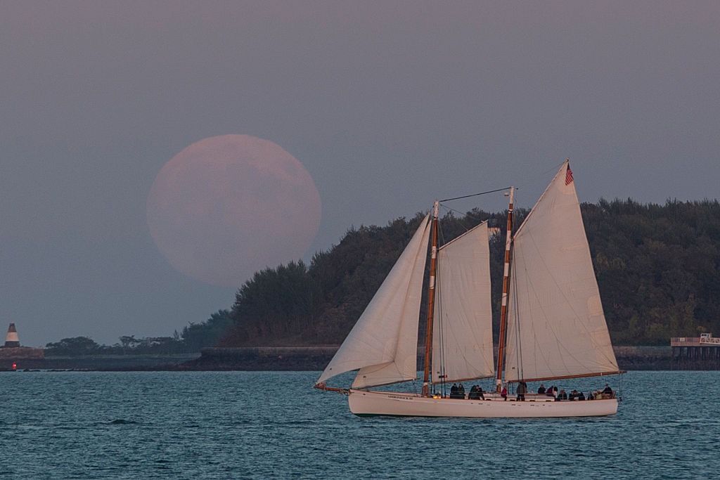 The supermoon rises over a sailboat in Boston Harbor on Sept. 27, 2015. 