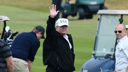 Donald Trump waves to fans on the golf course