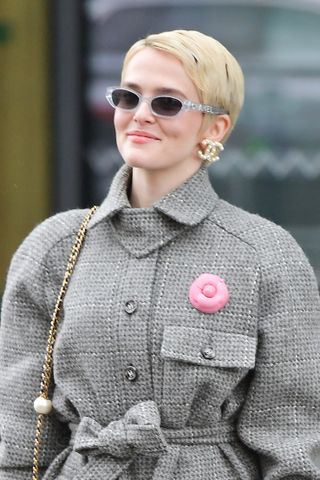 Zoey Deutch arrives at the Chanel fashion show in a tweed jacket and a blonde haircut