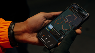 Person's hand holding phone showing Strava app in dark mode