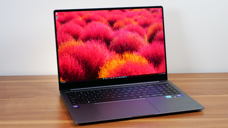 Samsung Galaxy Book 5 Pro slightly angled on a wooden table showing the desktop background on the display