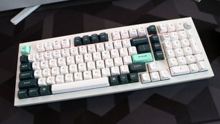 A Keychron Q5 HE gaming keyboard on a desk with white and blue keycaps.