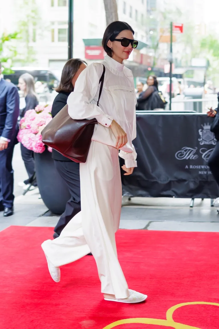 kendall jenner wears a white sporty jacket, white pants, and the row white slippers.