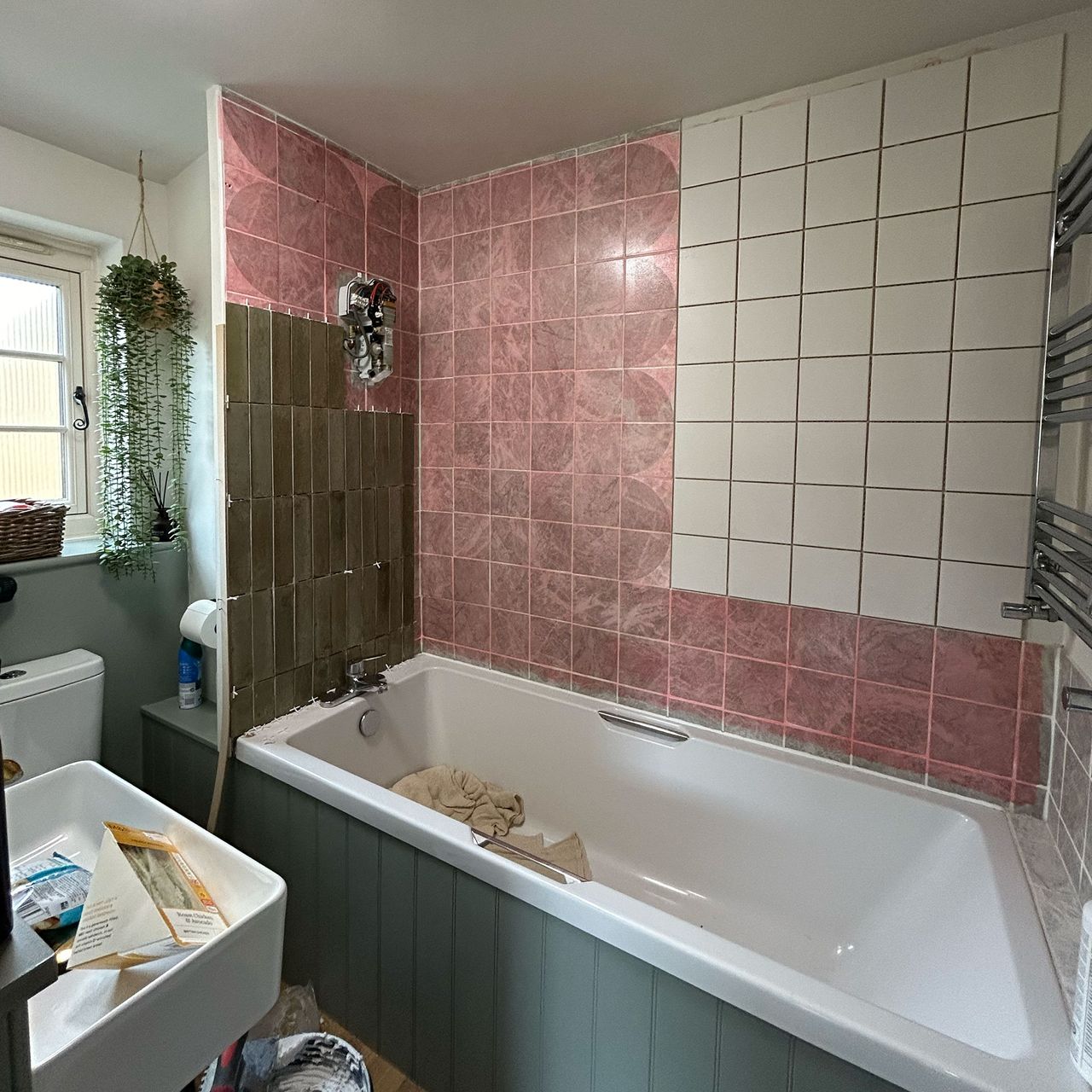 Bathroom mid-renovation with old white and pink tiles being covered with new green rectangular tiles