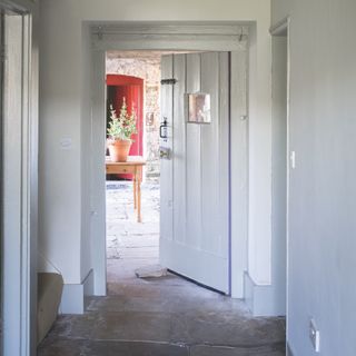 skirting board colour ideas, grey and white farmhouse style hallway, stone flags, doorway through to another room, grey skirting and woodwork