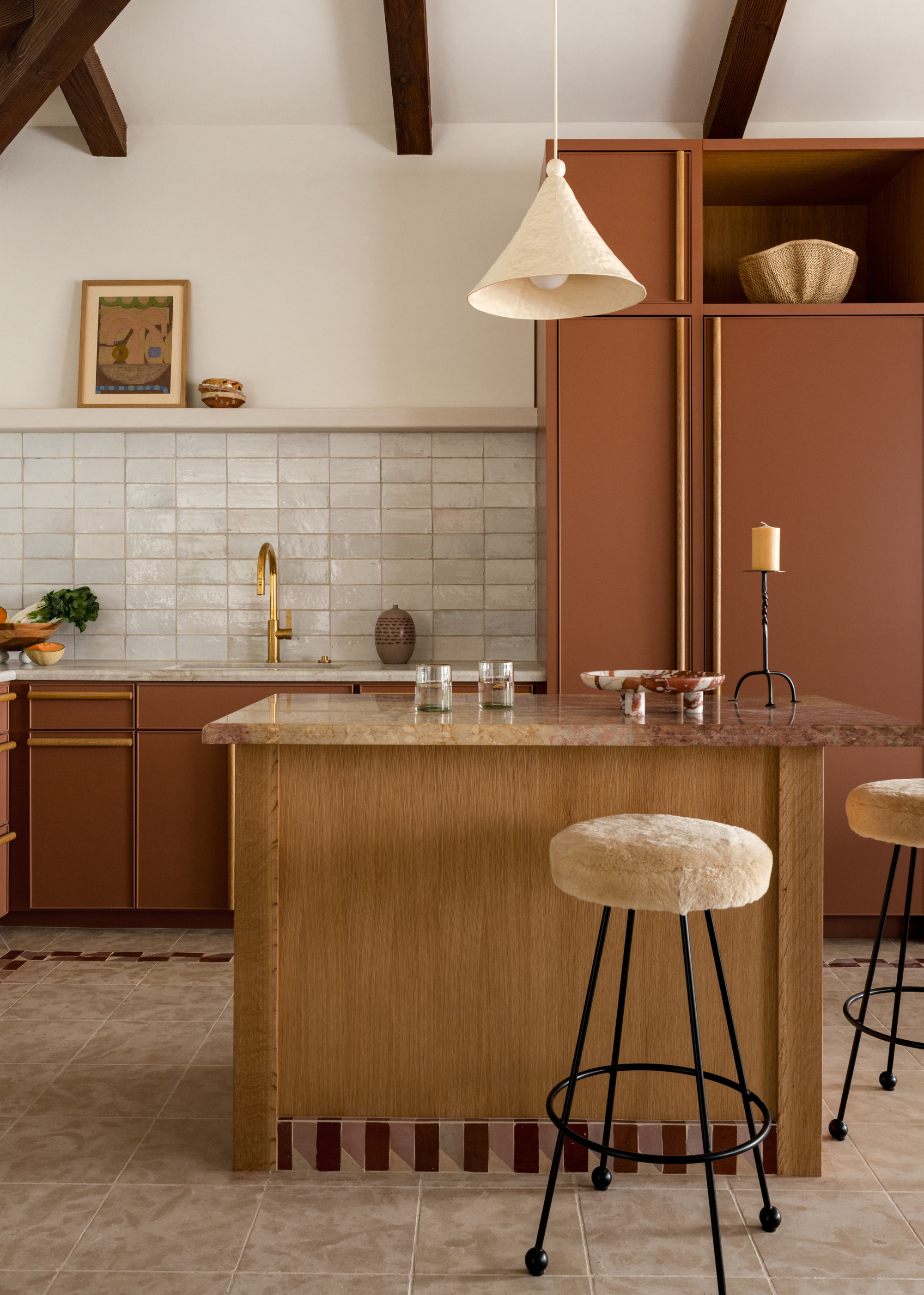 A modern traditional terracotta kitchen with a wood island a striped tile detail on the plinth
