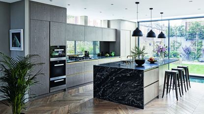 Modern fitted kitchen extension with grey wood-effect walls and black marble kitchen island on parquet floor