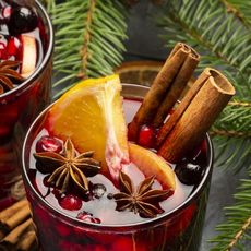 Two glasses of holiday cocktails with cinnamon, orange, and star anise