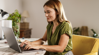 A woman on a laptop in a home office checking her emails