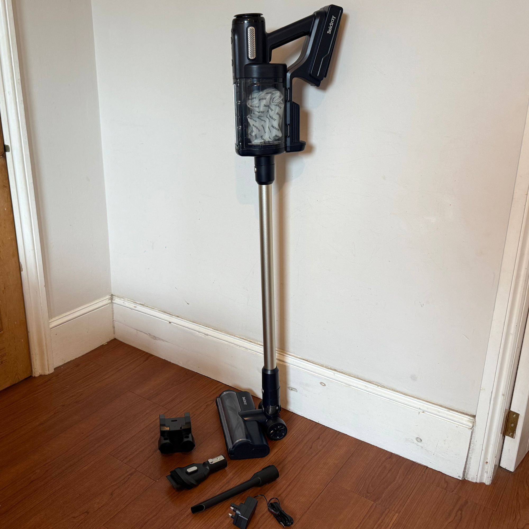 Beldray Airgo and the accessories leaning up against a white wall on wooden floors