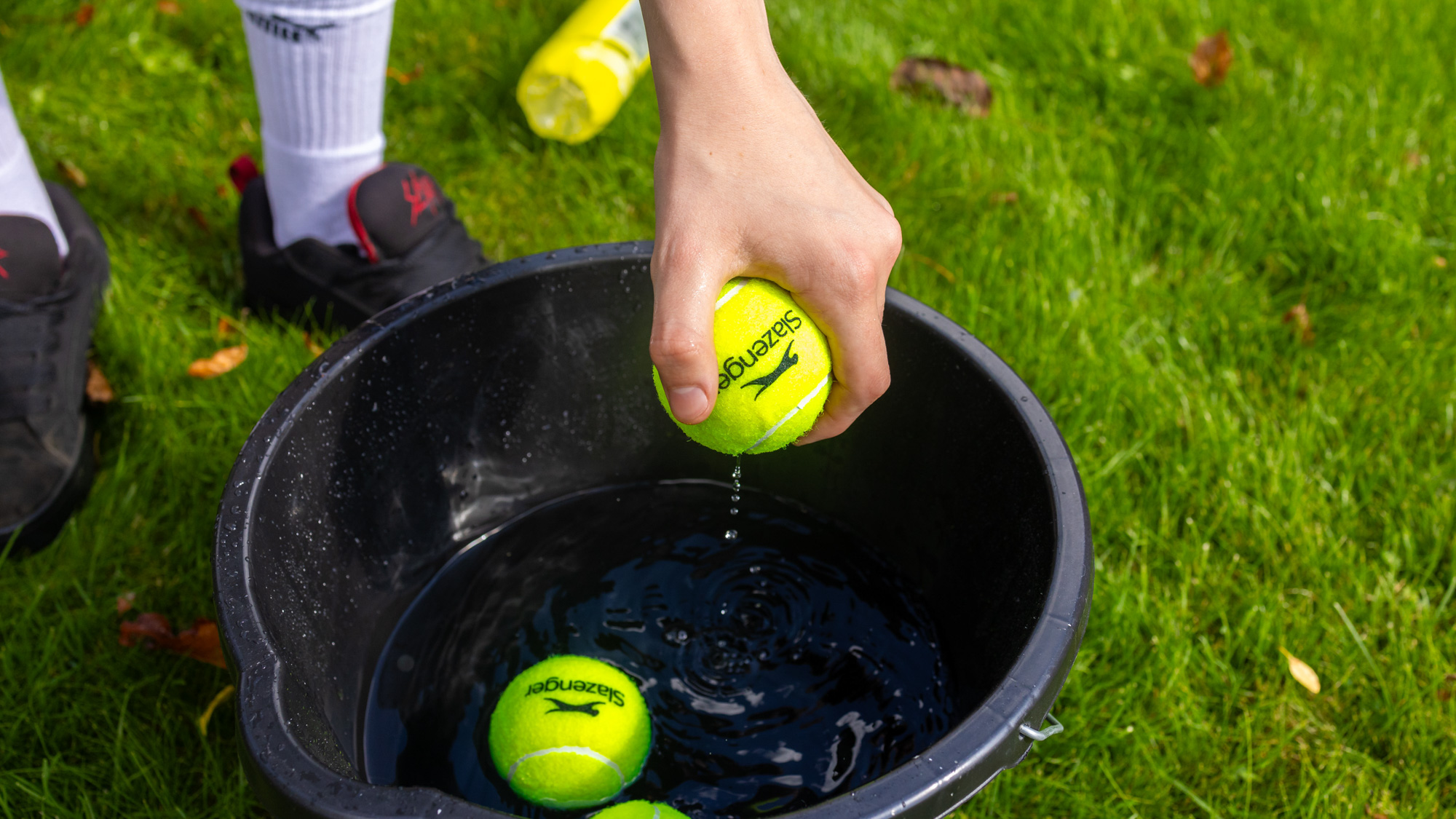 A close up of some wet tennis balls being dunked in a bucket of water