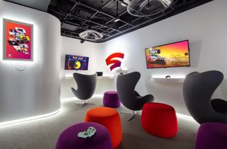 A Sandbox room in Google's New York Store, featuring gaming equipment, wide screens and upholstered seats in green, purple and red