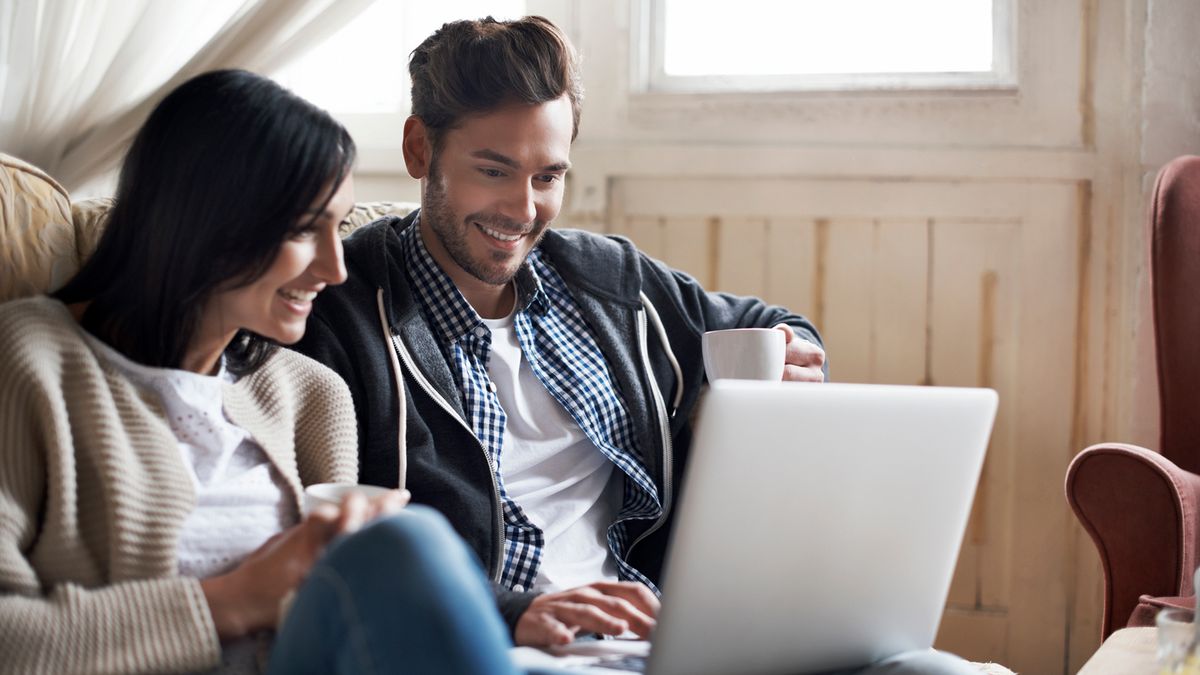 Couple looking happy surfing web on laptop