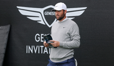 Scottie Scheffler looks at his yardage book before teeing off