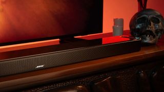 Bose Smart Ultra Soundbar on a stand in front of a TV with decorations