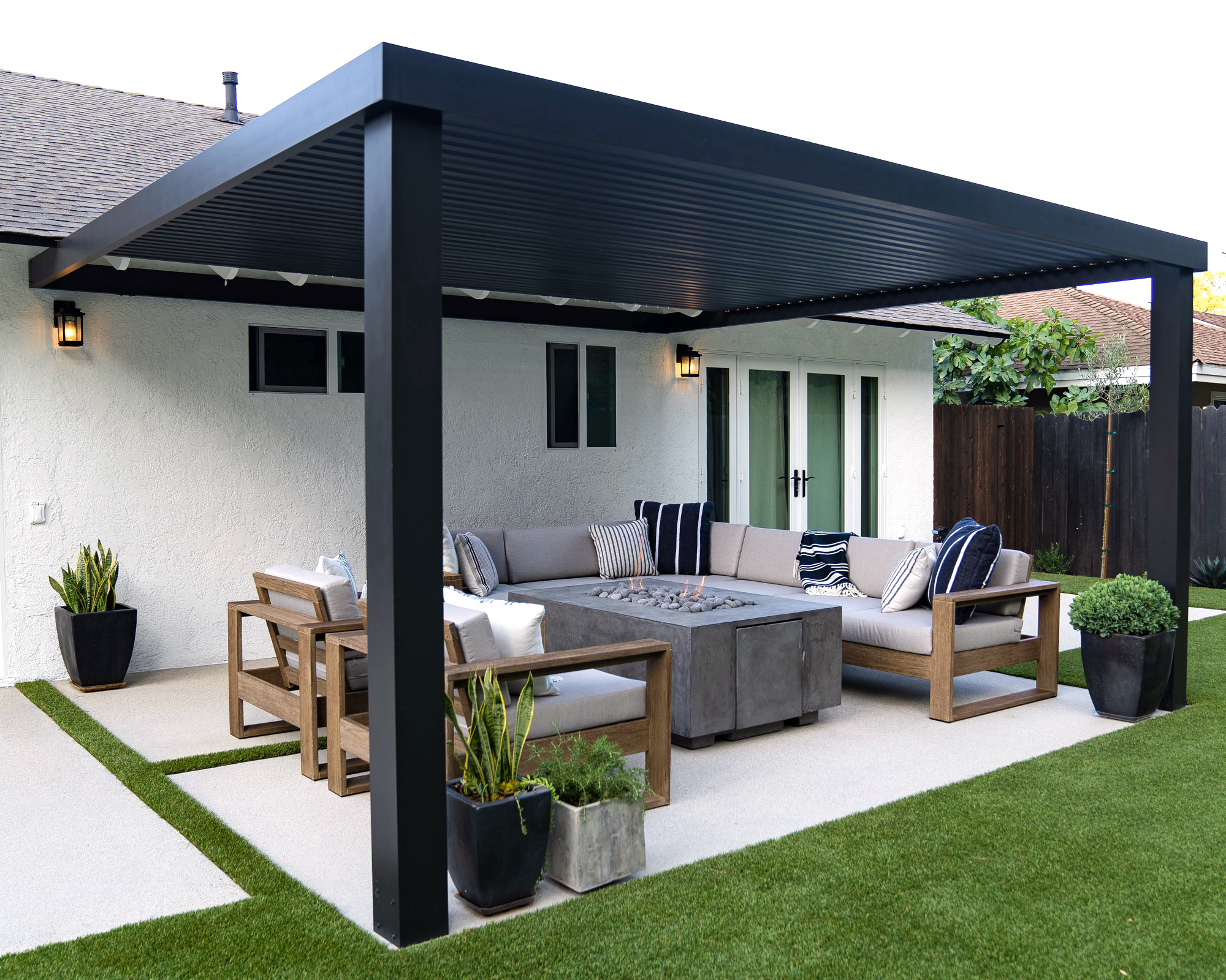 Louvred pergola with garden furniture and firepit on patio, plus planters and lawn